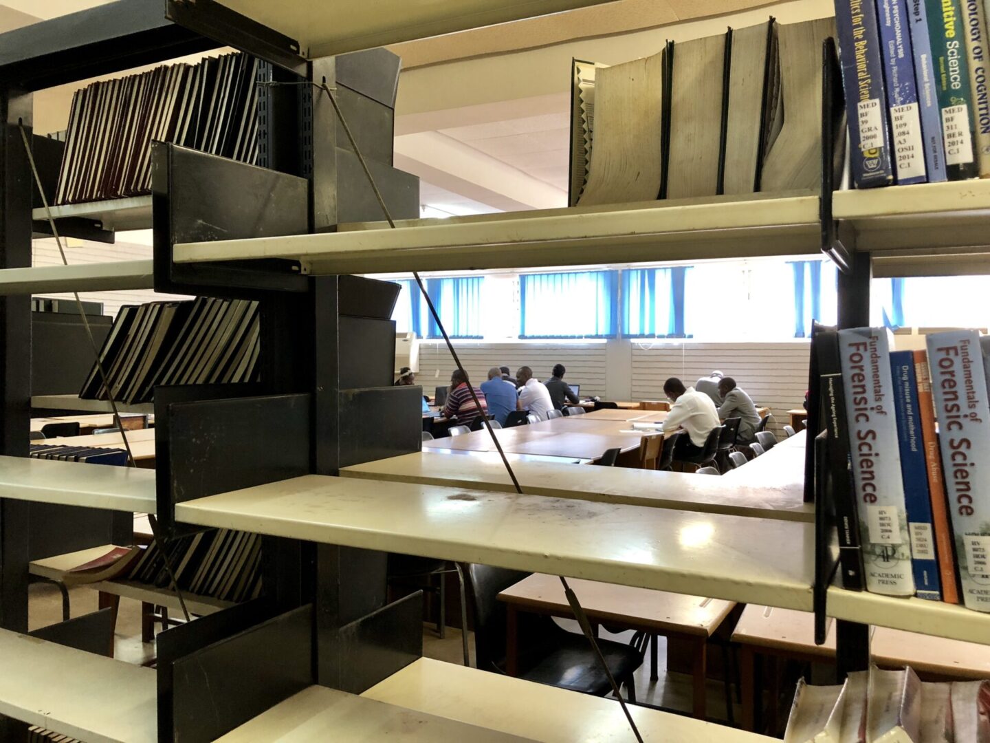 A group of people sitting at tables in front of shelves.